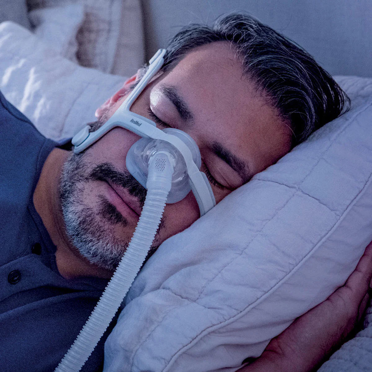 Man sleeping comfortably with resmed n20 mask and CPAP machine on white pillow