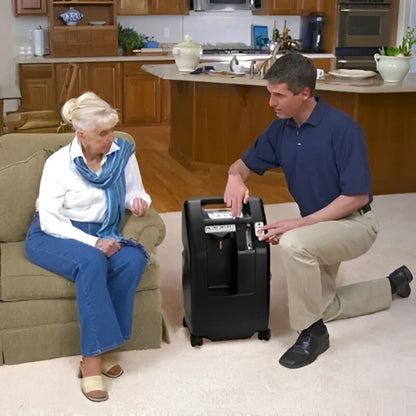 Man demonstrating Drive DeVilbiss 525 5L Oxygen Concentrator to elderly woman in living room