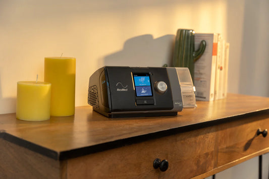 ResMed AirStart 10 CPAP machine on wooden table next to yellow candles and a cactus decor
